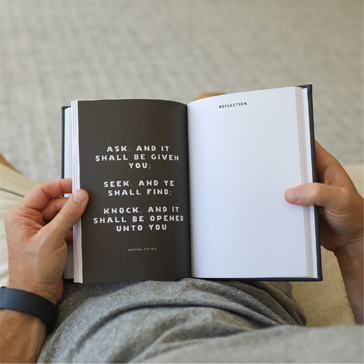 Person holding an open book with a motivational quote on a neutral background