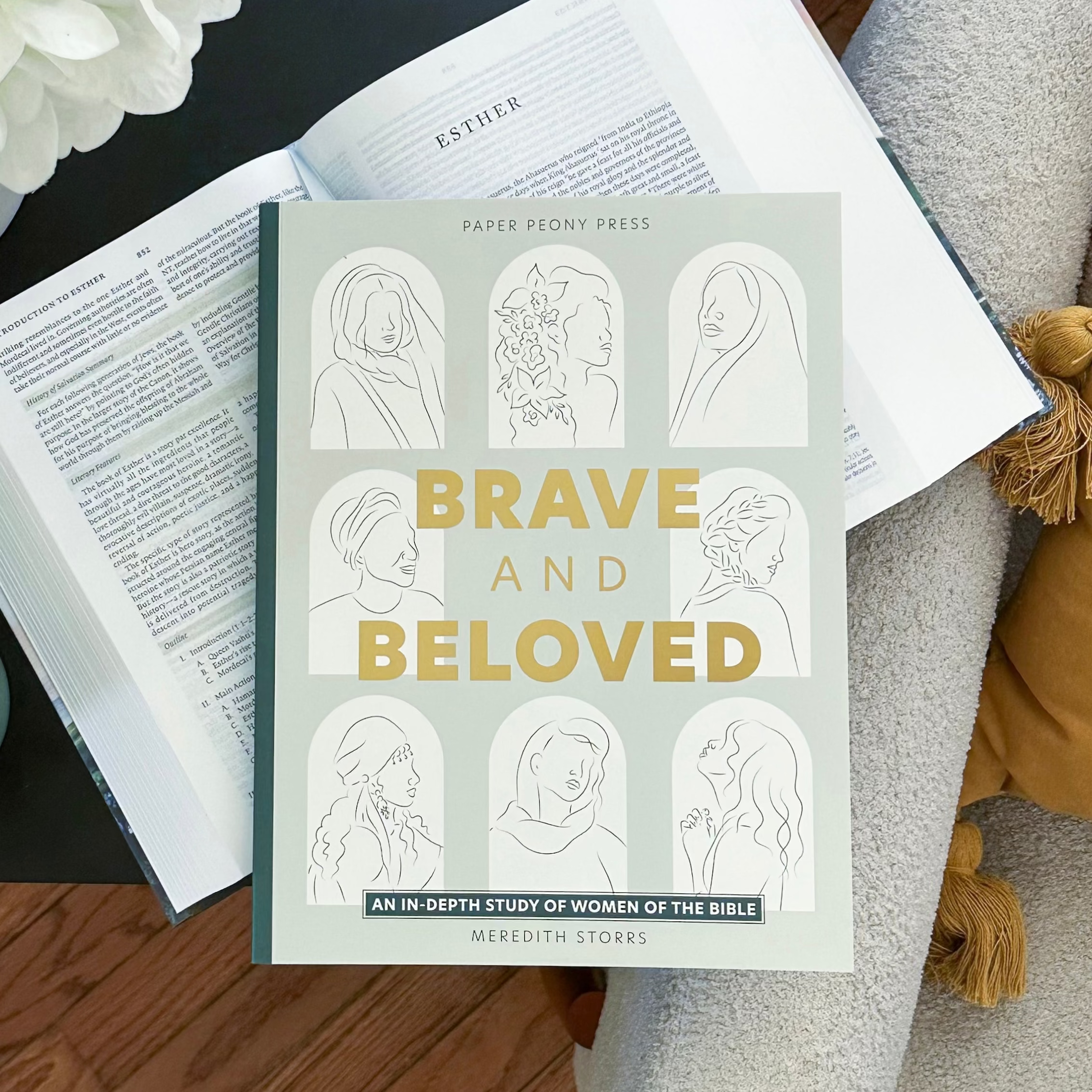 Book titled 'Brave and Beloved' on a table with flowers and a cup of coffee.