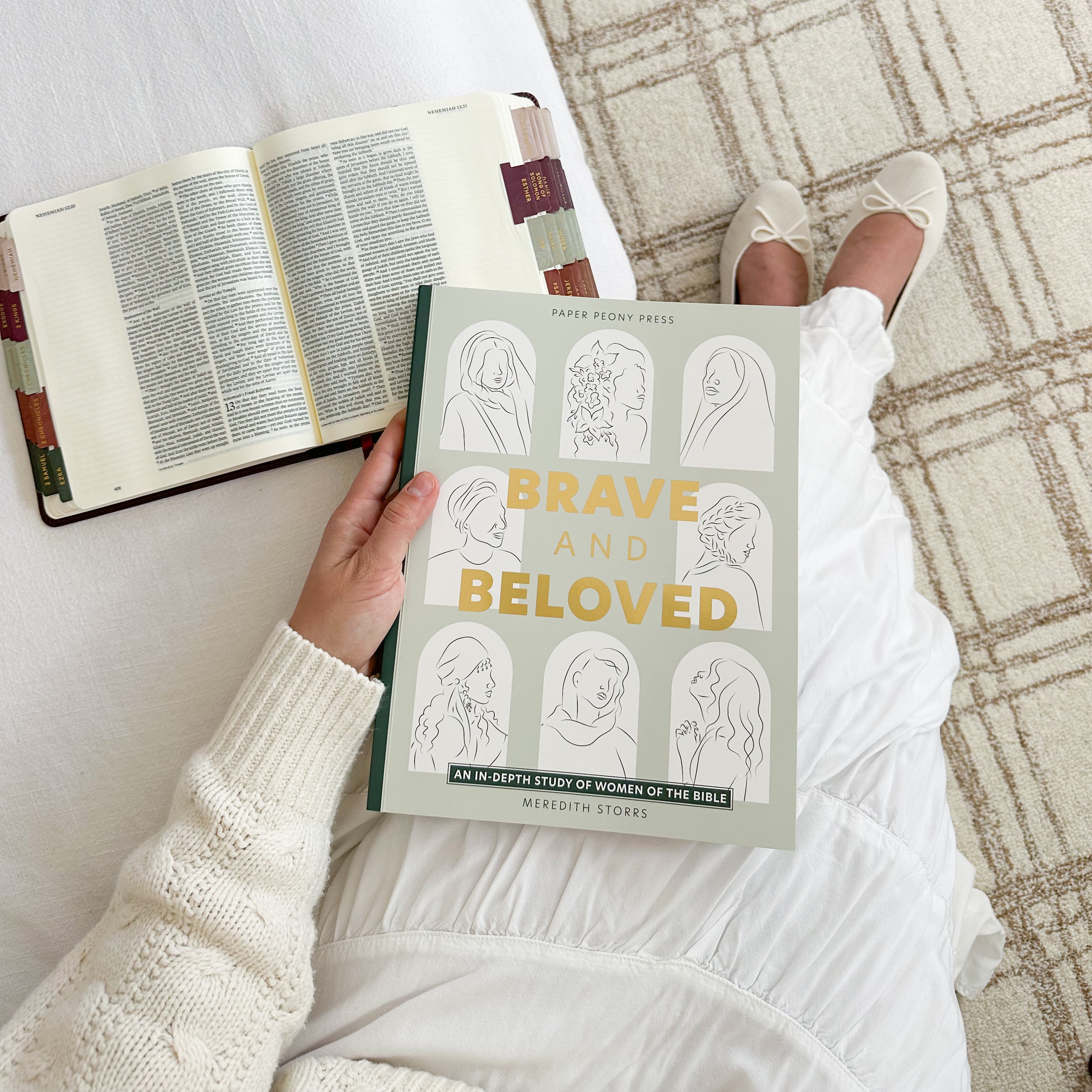 Person holding a book titled 'Brave and Beloved' on a textured surface