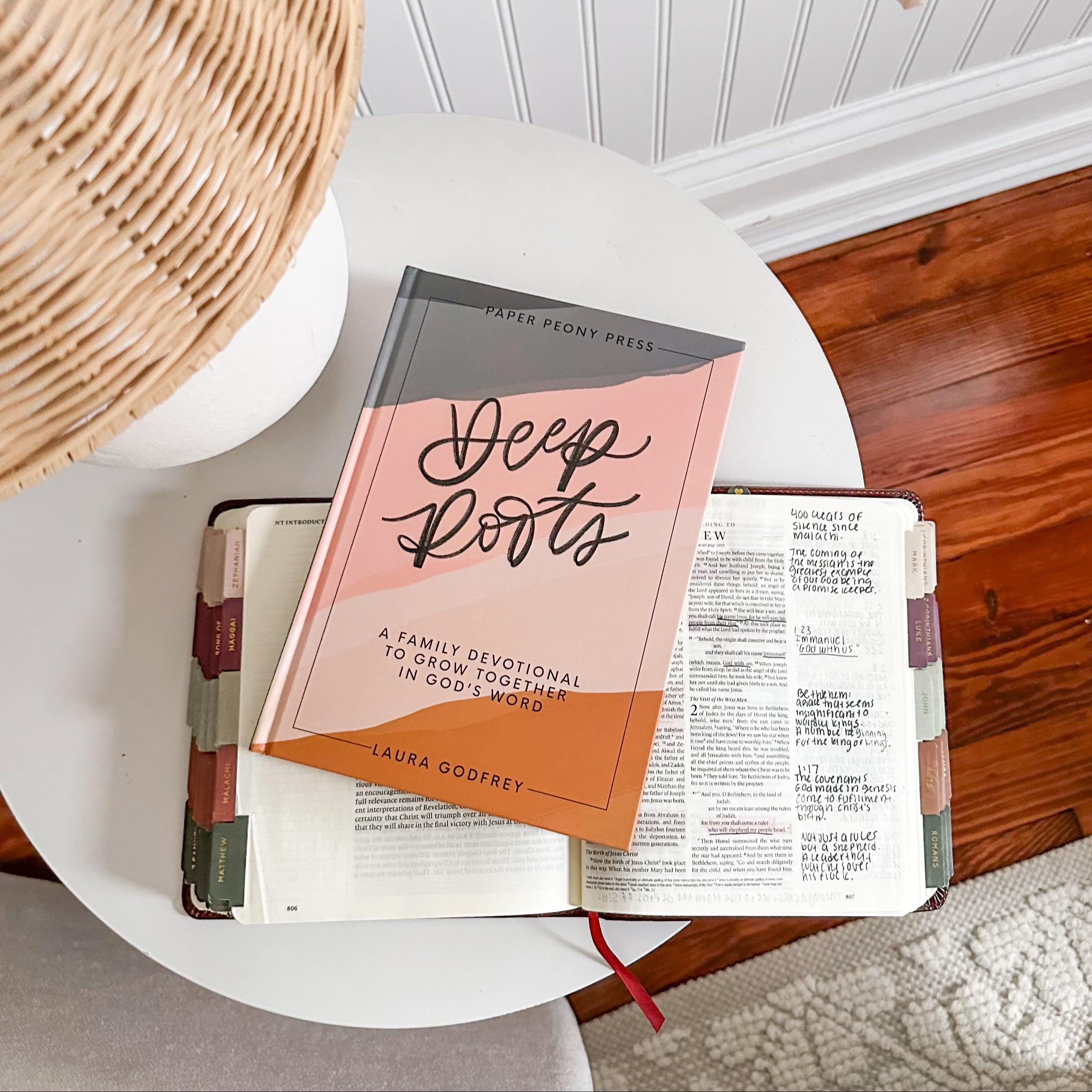 Book titled 'Deep Roots' by Laura Godfrey on a table with a woven basket.