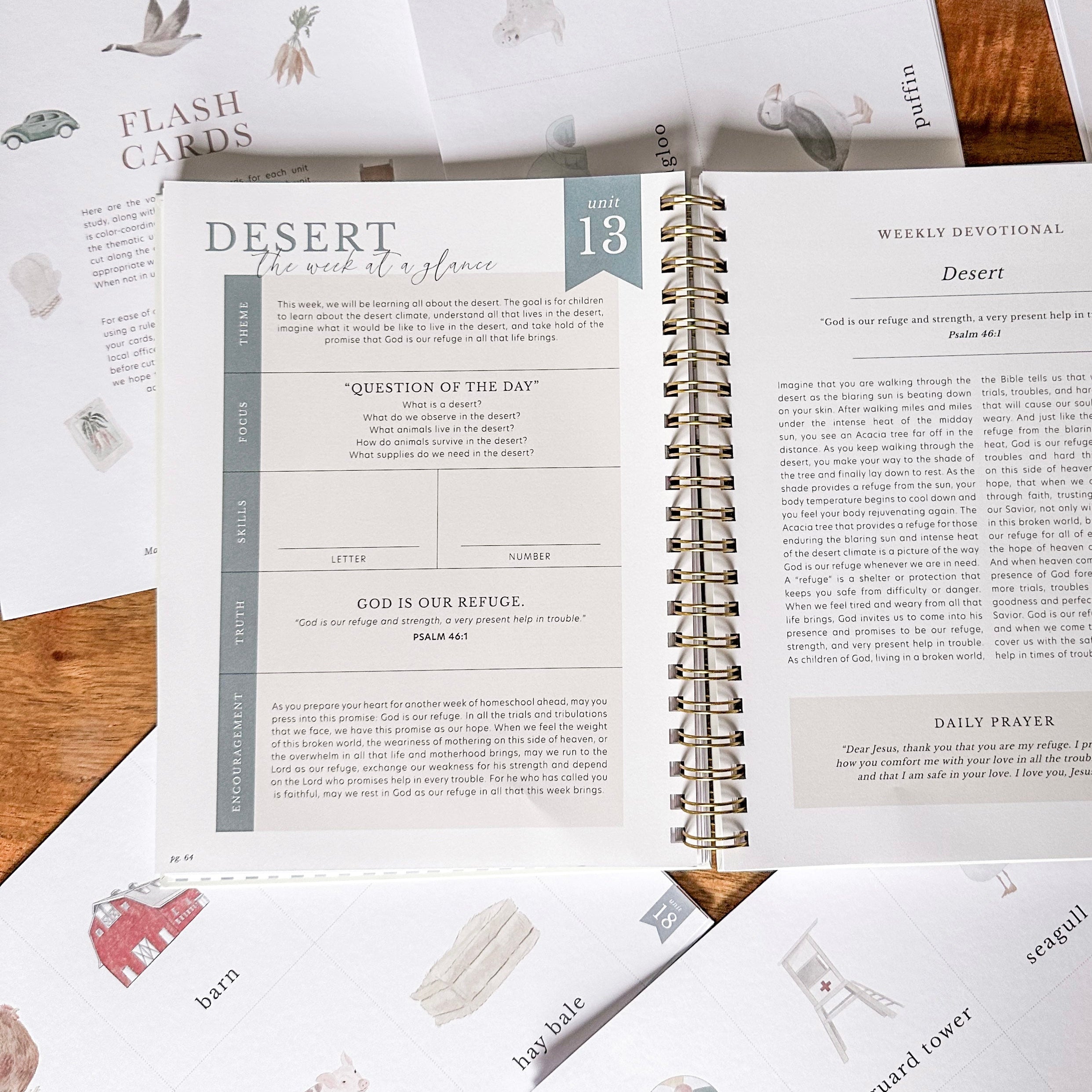 Open spiral-bound book with religious text and illustrations on a wooden surface