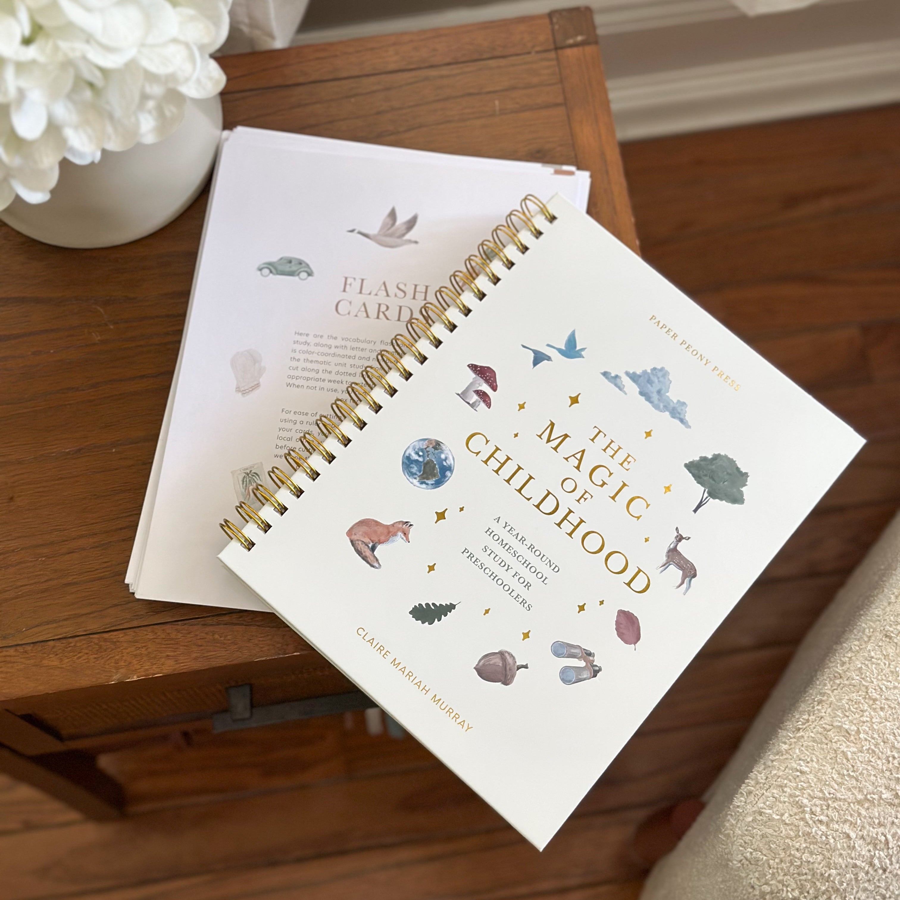 Notebook titled 'The Magic of Childhood' on a wooden surface with flowers in the background
