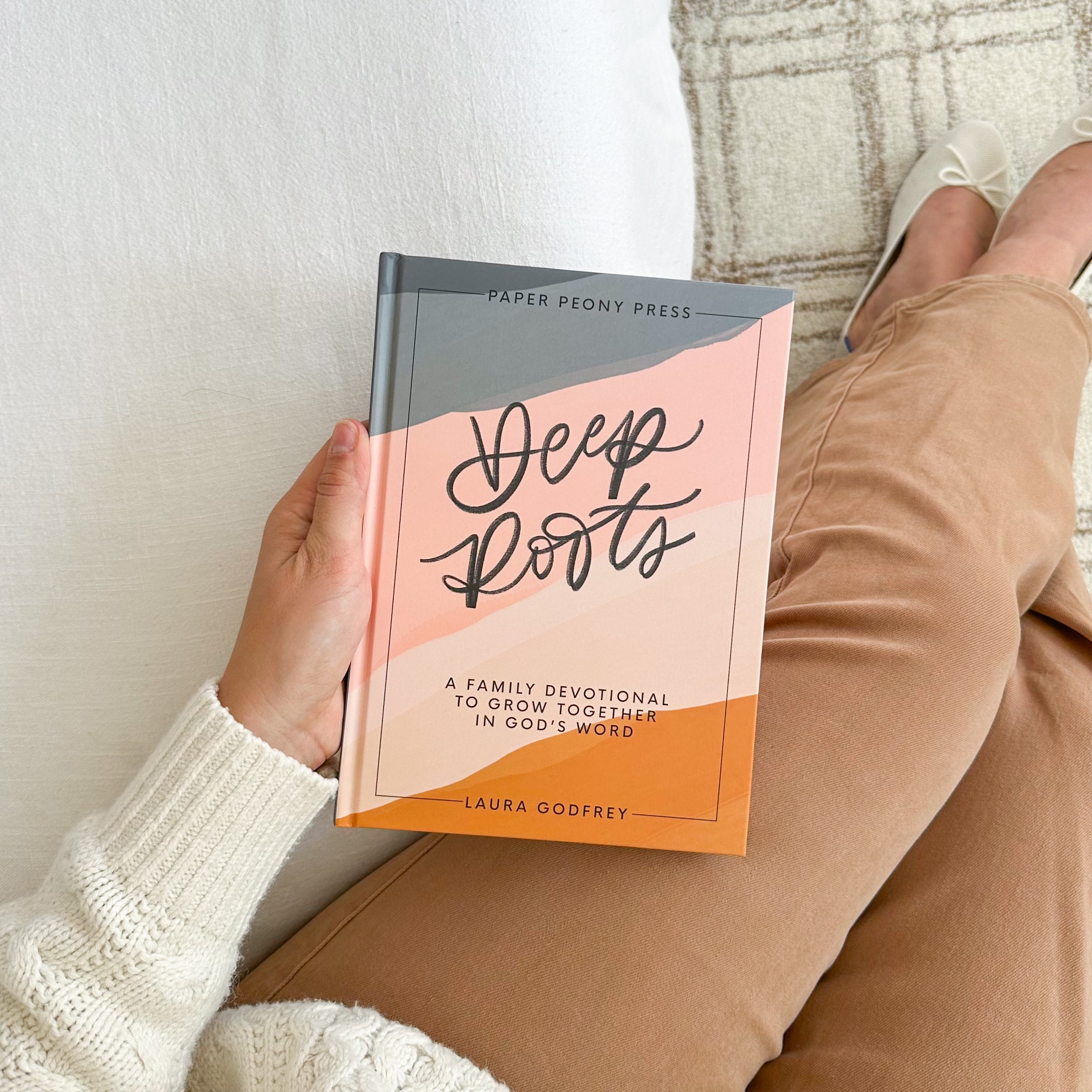 Person holding a book titled 'Deep Roots' by Paper Peony Press