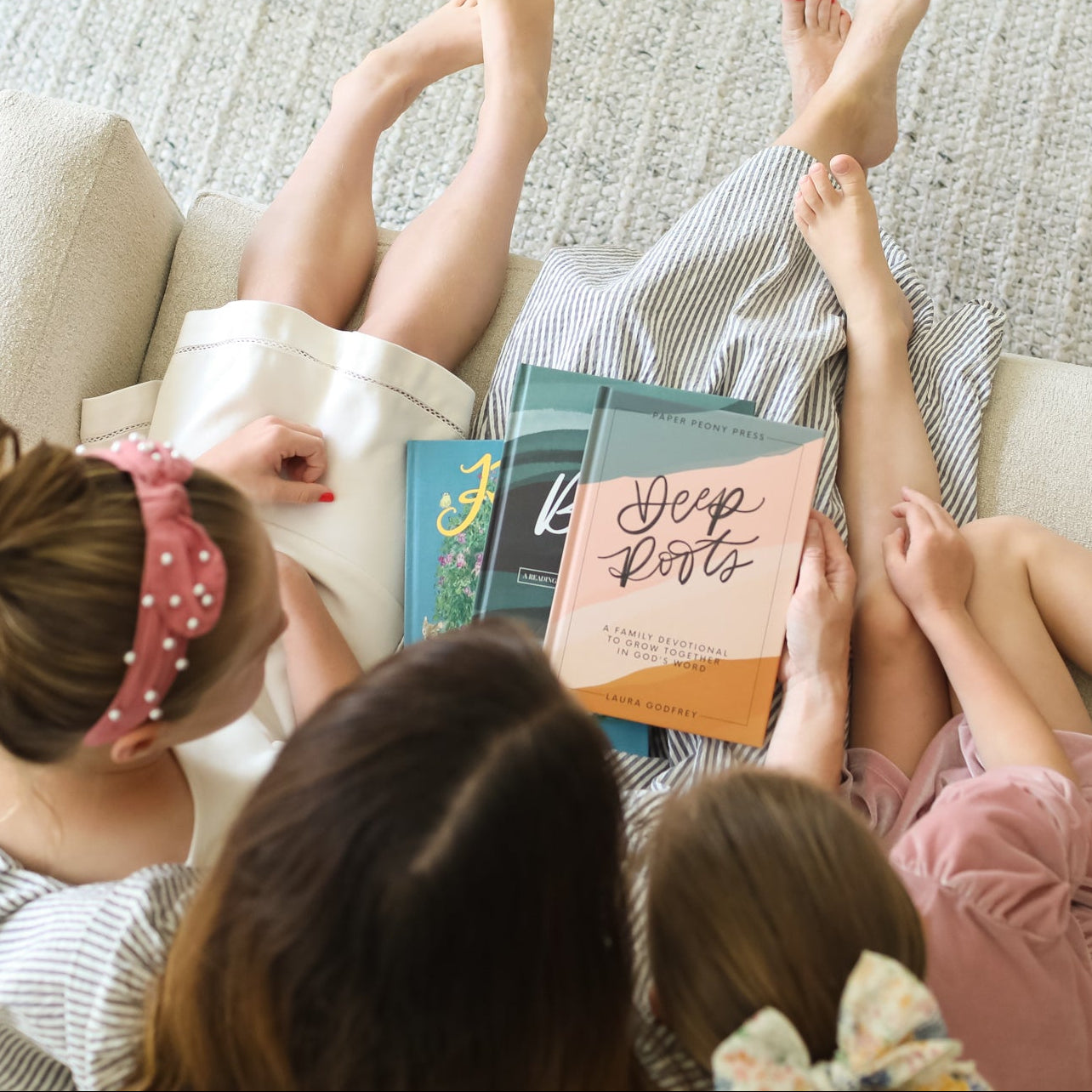 Three children sitting on a couch with books, surrounded by soft lighting.